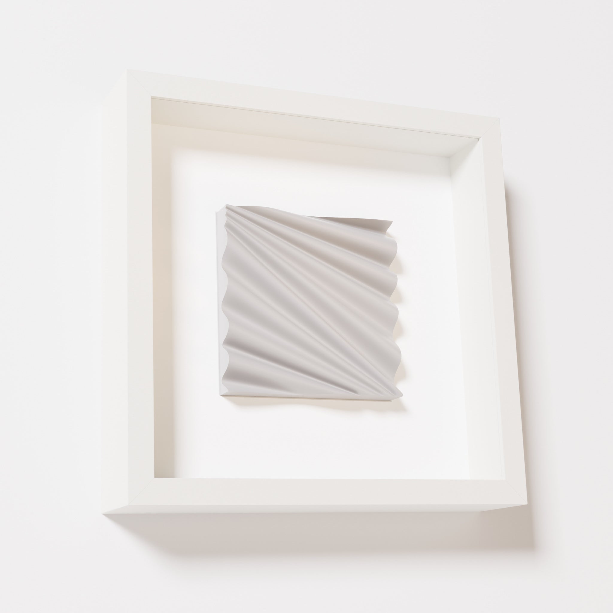 A close-up of a white shadowbox frame containing a marble white artwork featuring the rhythmic crests and troughs of 'Wave,' emphasizing its smooth texture and dynamic design.