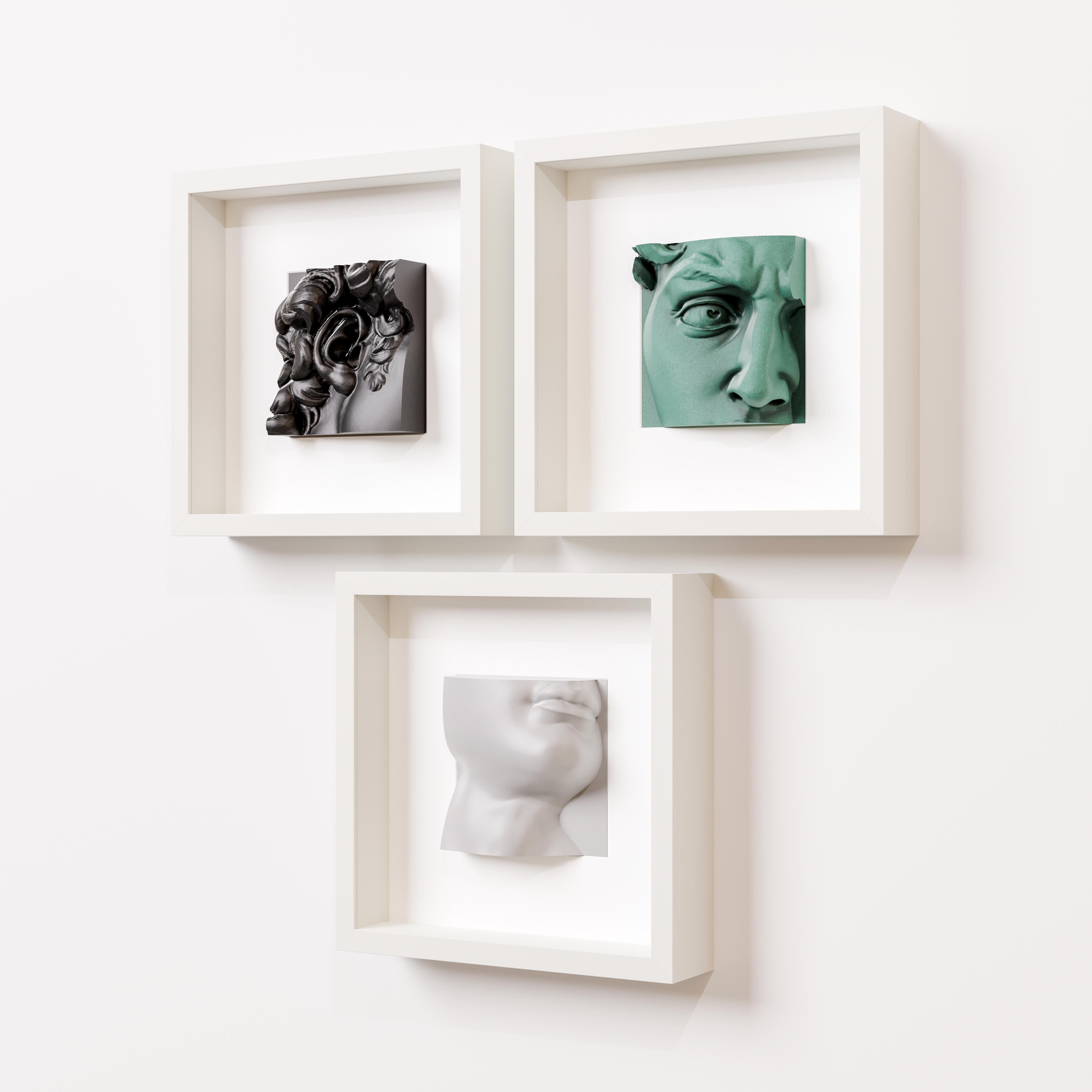 A minimalist arrangement of three white shadowbox frames, each showcasing a unique 3D sculpture: a black intricate Baroque-inspired design, a green classical eye detail, and a white modern profile of a face. Mounted on a clean white wall, this art display highlights a blend of textures, colors, and artistic styles, perfect for contemporary interior decor.